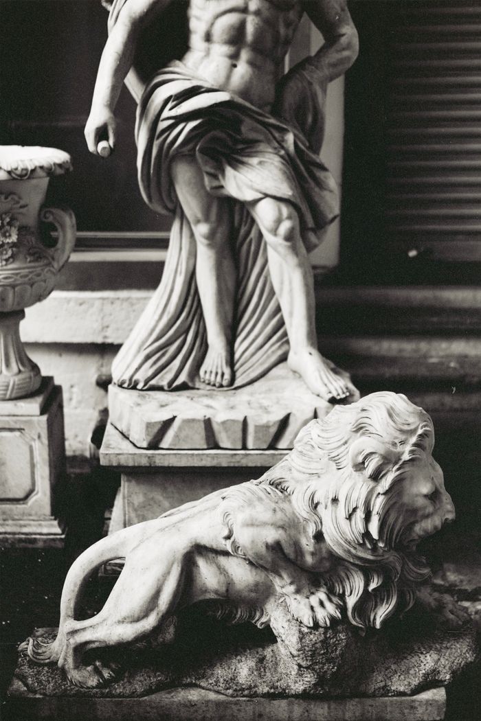 Black and white photo of classic marble statues, including a lion and human figure.